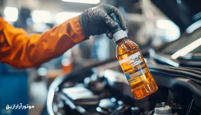 مکانیکی در حال نگه داشتن بطری روغن موتور با برچسب گرید 0W-20 در نزدیکی موتور خودرو برای بررسی مصرف بهینه سوخت