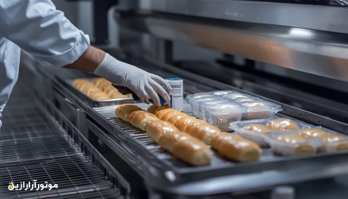 نمای بسته از اپراتور صنعتی در حال استفاده از روانکار بهداشتی با تأییدیه NSF در خط تولید نان بسته‌بندی‌شده – محیط استریل و کاملاً بهداشتی در کارخانه صنایع غذایی