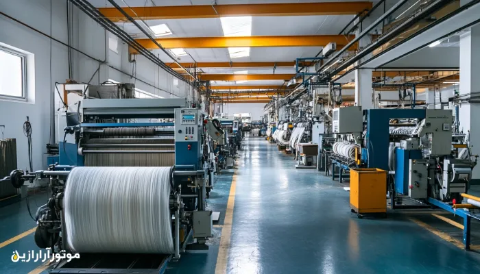 نمای عریض از سالن تولید کارخانه نساجی با ردیف‌هایی از ماشین‌آلات مدرن بافندگی و چاپ – محیط صنعتی پاک و پیشرفته با خطوط تولید فعال