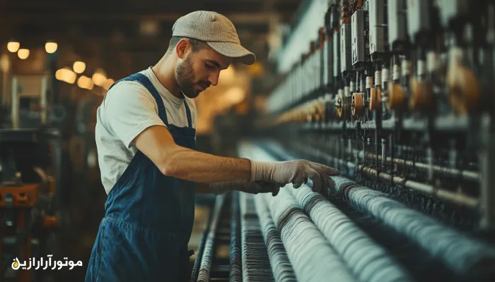 تکنسین کارخانه نساجی در حال بررسی عملکرد دوک‌های ریسندگی در خط تولید نخ – نمایی از دقت و مهارت در تنظیم ماشین‌آلات صنعتی سبک