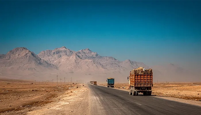 کامیون‌های باری در جاده کویری یزد با پس‌زمینه کوهستان | روغن موتور دیزلی یزد