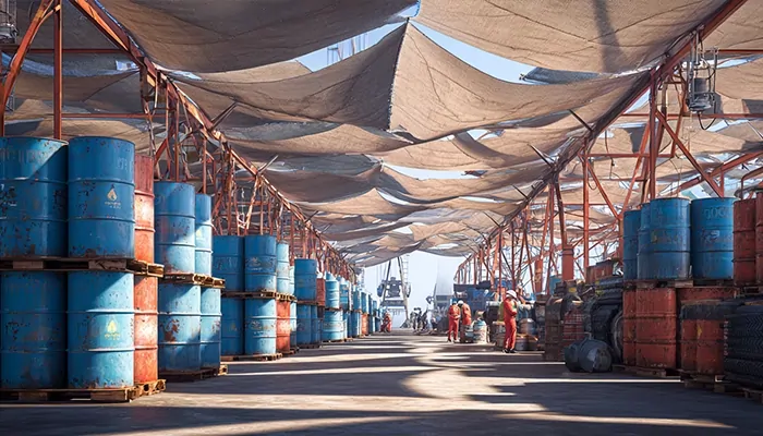 انبار بزرگ بشکه‌های آبی روغن صنعتی در بندر با نظارت کارگران و آماده برای پخش عمده