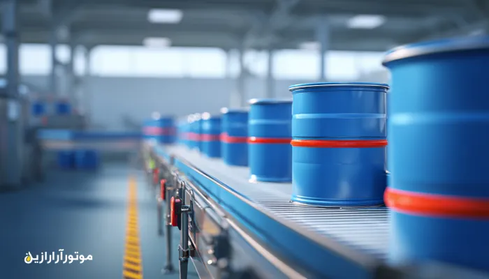 نمای داخلی خط بسته‌بندی محصولات کشاورزی در میاندورود با نوار نقاله استیل و بشکه‌های آبی موتورازین در پس‌زمینه. روغن صنعتی میاندورود