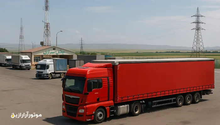 کامیون قرمز در پایانه مرزی بیله‌سوار با چشم‌انداز دشت و برج‌های برق